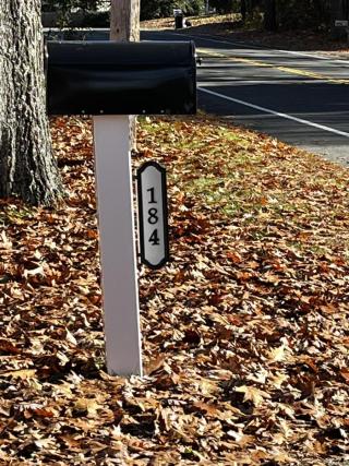 white mailbox post with black mailbox and white and black house number sign 184