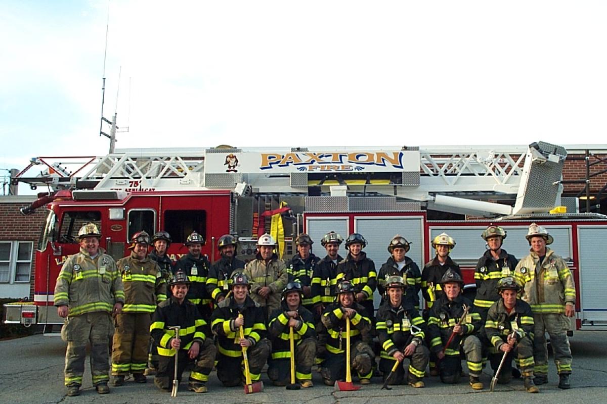 Fire crew in equipment uniform lined up in front of the ladder truck