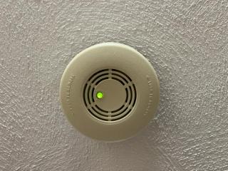 Beige smoke detector on white ceiling